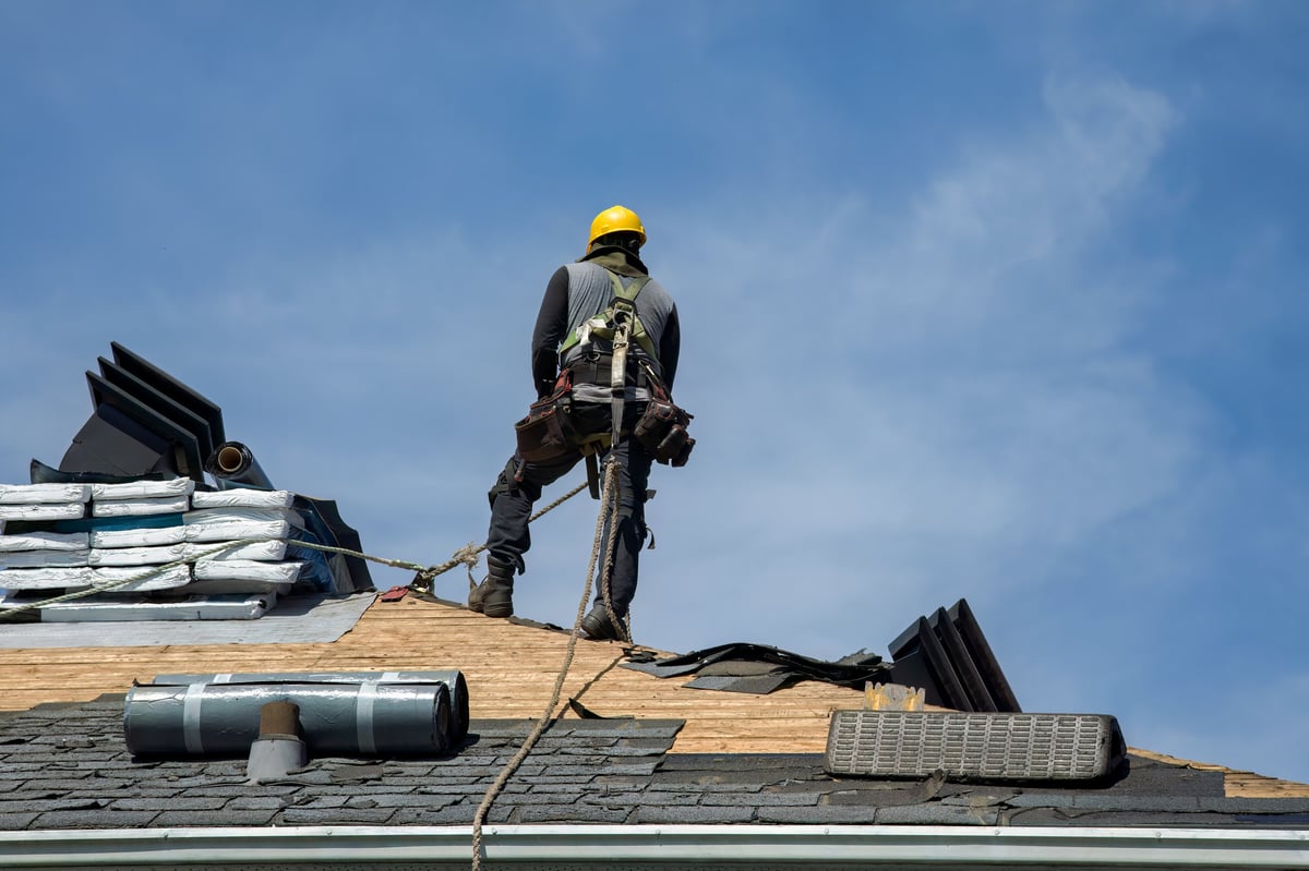 Professional roofing contractor working on residential house roof with modern equipment
